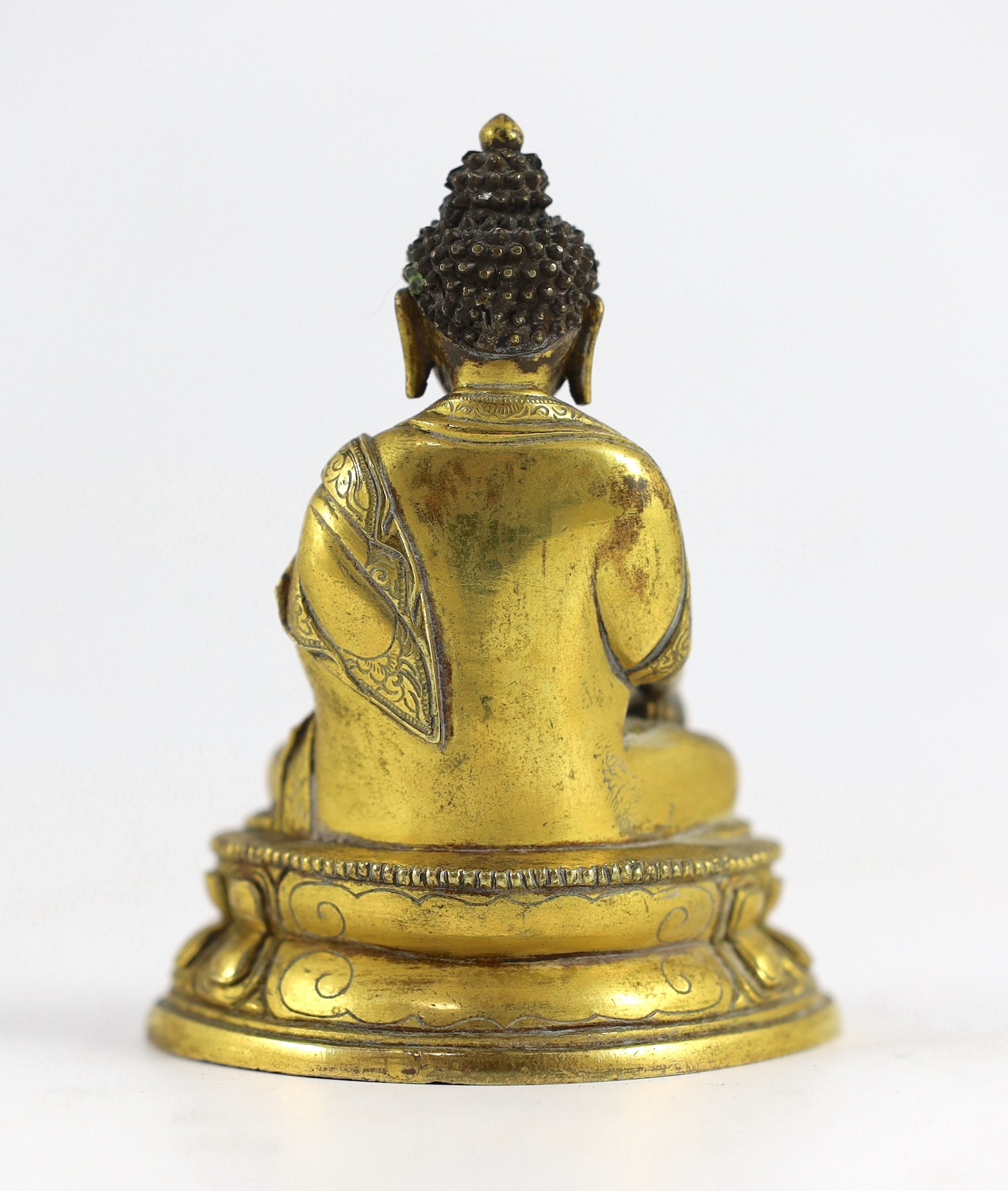 A small Tibetan gilt bronze seated figure of Buddha Shakyamuni, 18th century, 9.5cm high, lacking bowl in left hand
